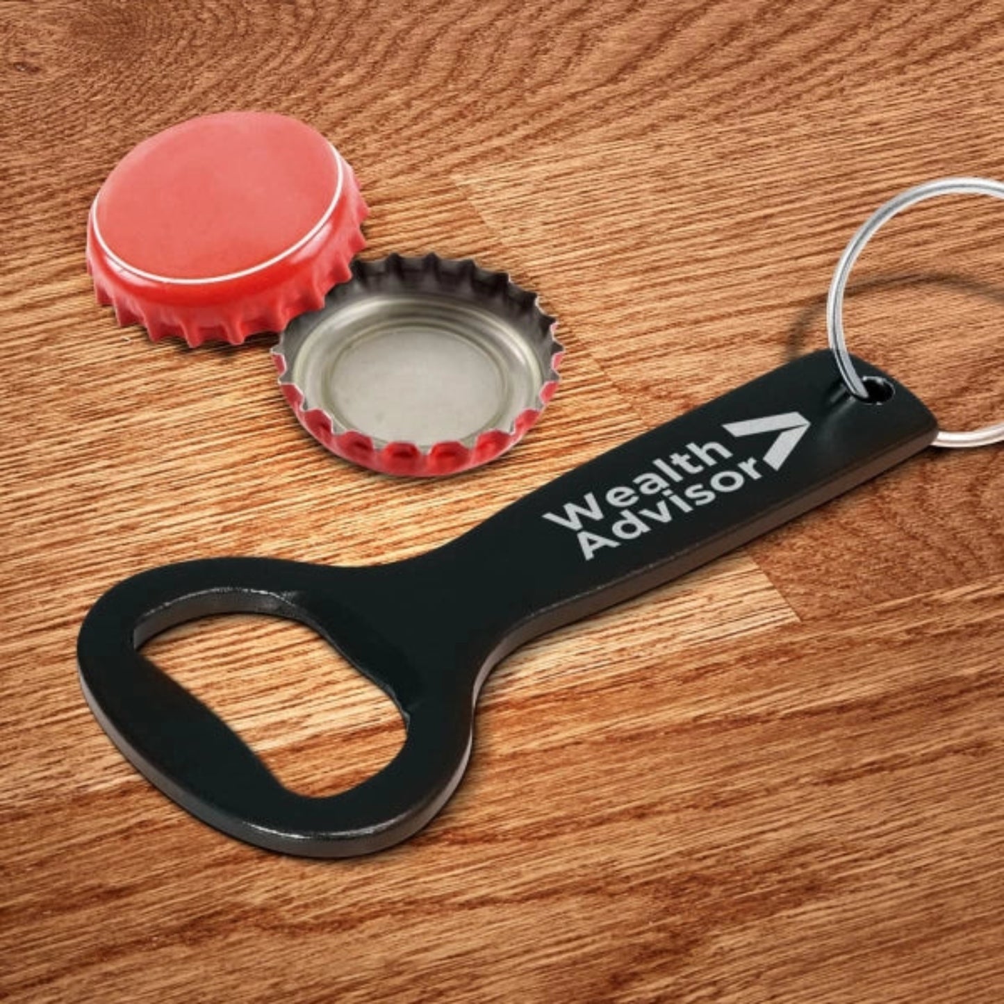 Black bottle opener with 'Wealth Advisor' text on a wooden surface with bottle caps.