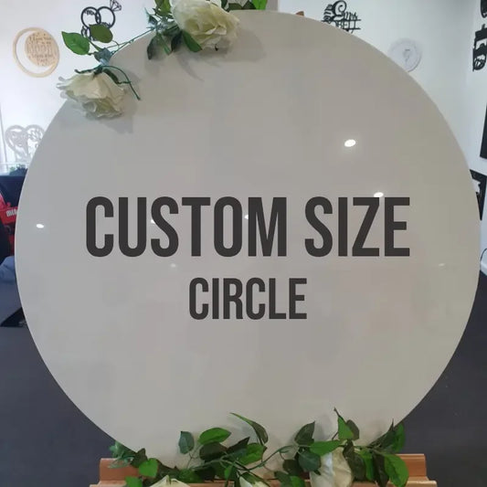 Custom size circle sign with white flowers and greenery on display indoors