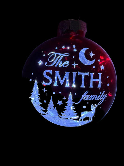 Personalized red Christmas ornament with 'The Smith family' text, moon, deer, and pine trees