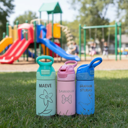 Three personalized water bottles with names and designs on a wooden surface.