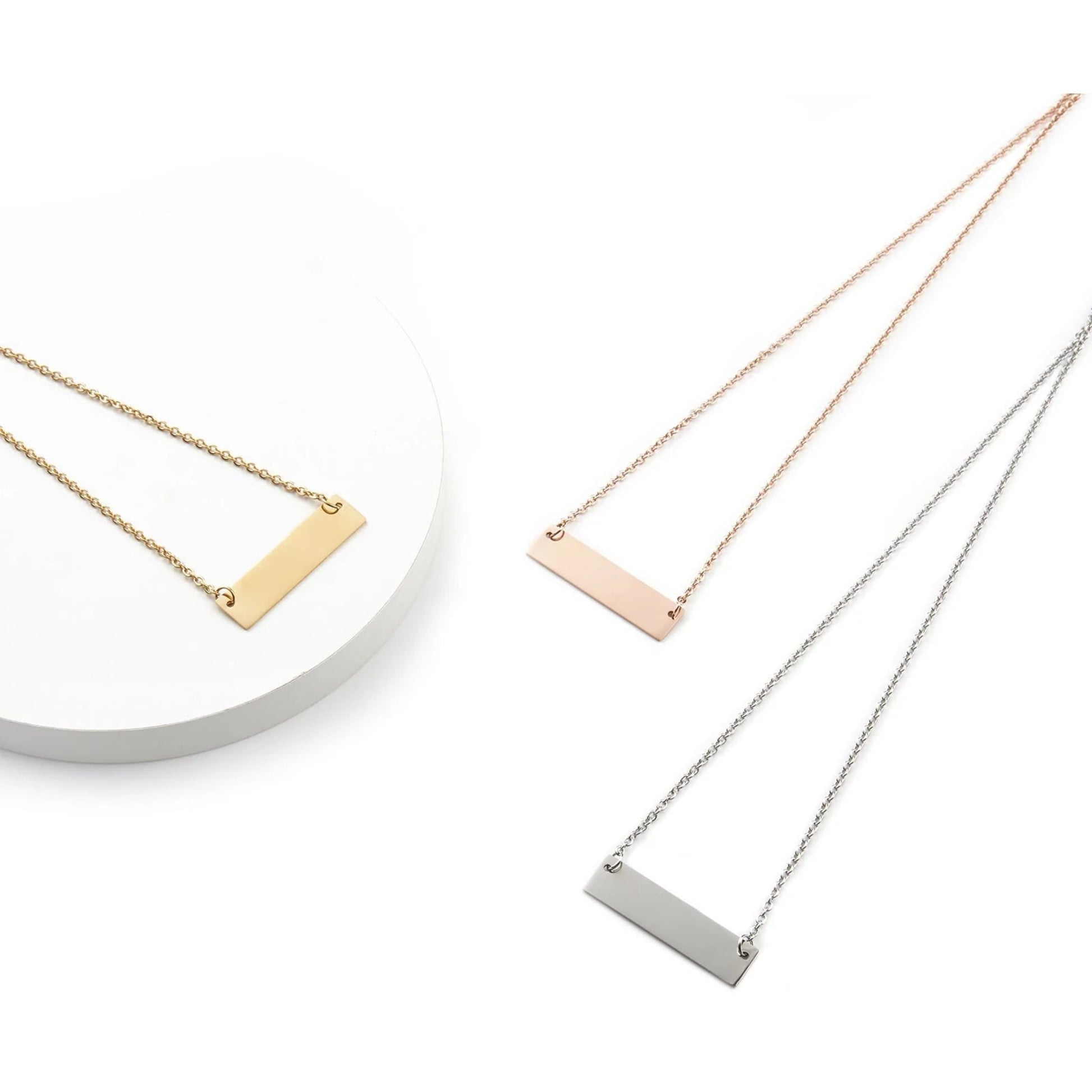 Three necklaces with horizontal bar pendants in gold, rose gold, and silver on a white background.