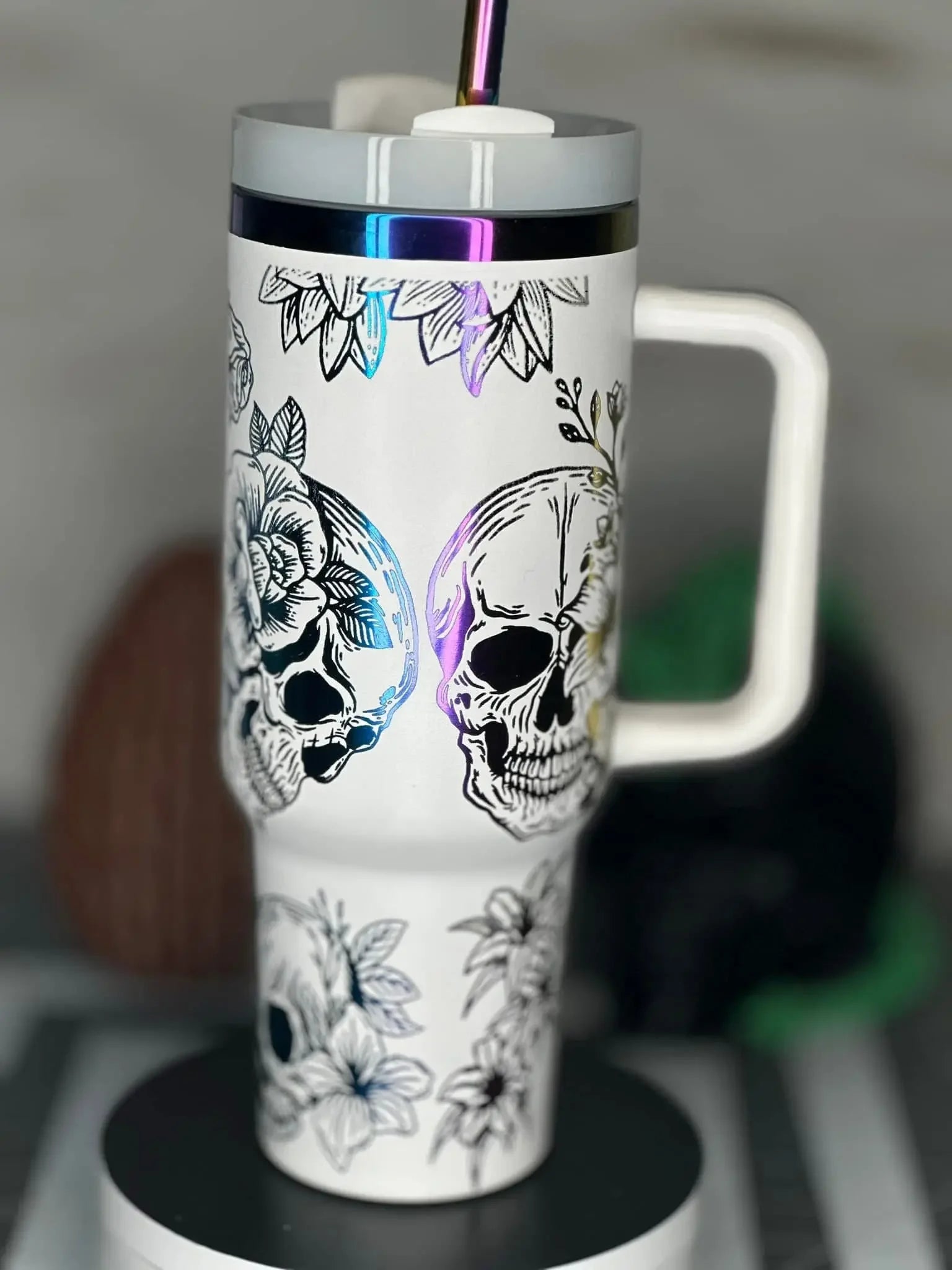 White tumbler with handle featuring black floral and skull designs, iridescent straw lid