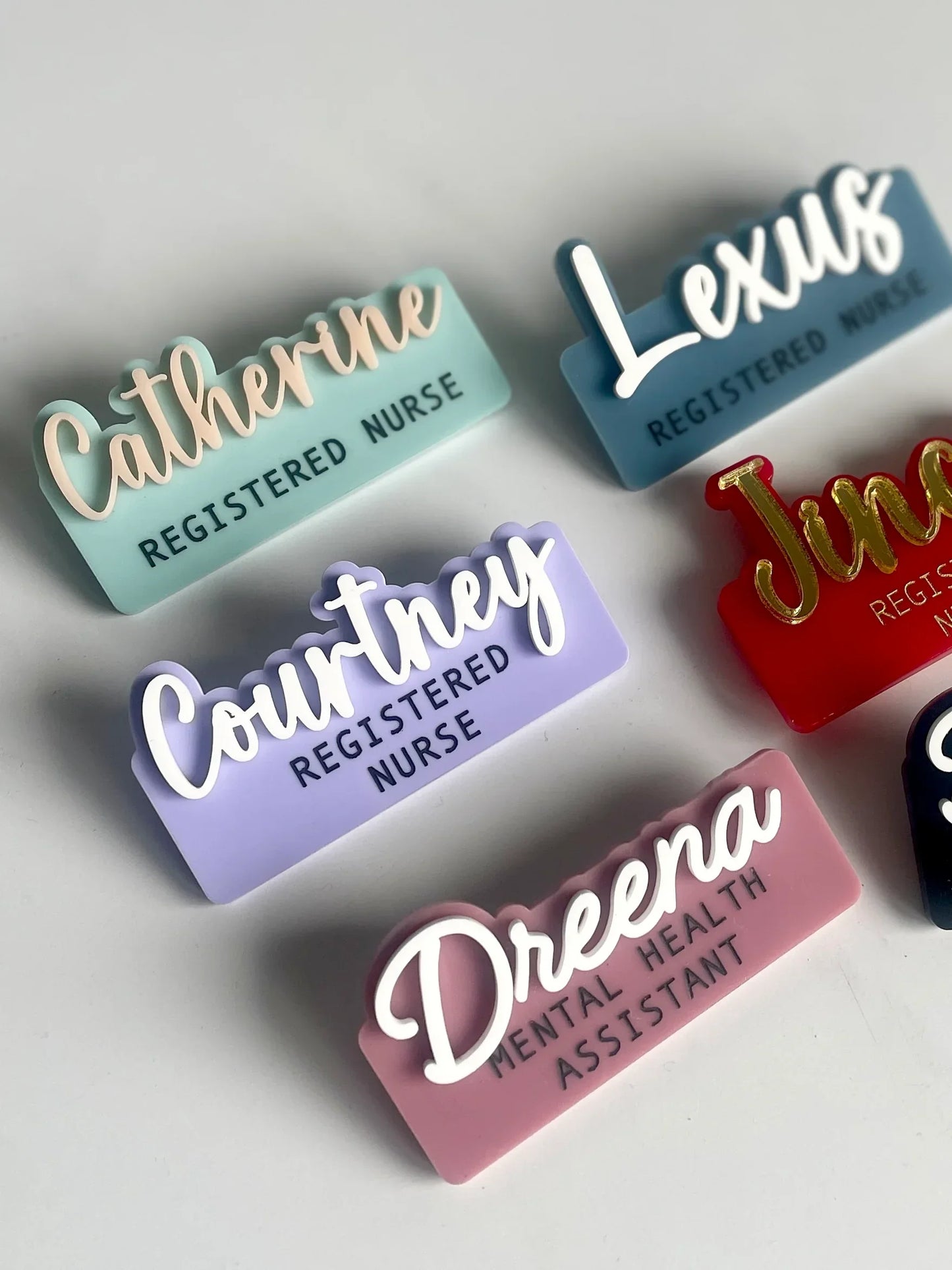 Colorful custom nurse and mental health assistant name badges with engraved titles on a white background